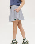 A seersucker skirt with subtle stripes, featuring a flat drawstring, faux buttons down the front, and side seam pockets.