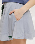 A person wearing a blue top and a patty skirt with indigo stripes. The skirt is knee-length and has a drawstring waist.