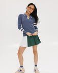 A woman wearing a pleated green and white skirt with a round drawstring waist, colorblocking, and a 'Chasing Balls' icon patch on the back.