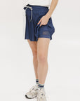 A pleated skirt with colorblocking in indigo and white, featuring a round drawstring cord at the waist and a 'Chasing Balls' icon patch on the back.