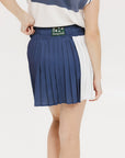 A pleated skirt with colorblocking in indigo and white, featuring a round drawstring cord at the waist and a 'Chasing Balls' icon patch on the back.