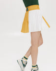 A person wearing a mustard pleated skirt with colorblocking, featuring a round drawstring cord.