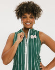 A woman wearing a sleeveless, v-neck, pinstripe green and white dress with a belt.