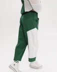 A pair of color-blocked green and white warm-up pants with a pink stripe, featuring a flat drawstring waistband and deep front pockets, branded with the 'Fore All' detail on the back and an FA icon on the inner calf.