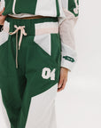 A pair of Caitlin Warm-Up Pants in green, pink, and white colors, featuring a drawstring waist and number '04' on the leg.