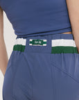 A pair of indigo and green color-blocked warm-up pants with a flat drawstring waistband, deep front pockets, and a barrel style fit. The pants feature appliqué logos, including the 'Fore All' detail on the back and an FA icon on the inner calf.