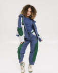A person wearing a blue and green warm-up pants with matching jacket, standing against a white background.