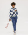 A person wearing the Simone Pant in blue with white stripes on the side, featuring princess seams down the leg and a slit at the hem. The person is also wearing a checkered blue and white top and white sneakers.