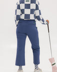 A person wearing the Simone Pant in blue with white stripes on the side, featuring princess seams down the leg and a slit at the hem. The person is also wearing a checkered blue and white top and white sneakers.