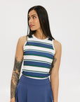 A woman wearing a sleeveless tank top with a striped pattern in blue and white colors, paired with a solid blue skirt.
