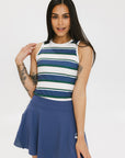 A woman wearing a sleeveless tank top with a striped pattern in blue and white colors, paired with a solid blue skirt.