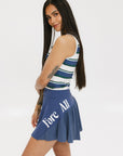 A woman wearing a sleeveless tank top with a striped pattern in blue and white colors, paired with a solid blue skirt.
