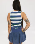 A woman wearing a sleeveless tank top with a striped pattern in blue and white colors, paired with a solid blue skirt.