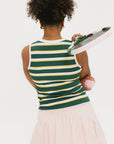 A person viewed from behind wearing a sleeveless mustard yellow and green striped tank top with white skirt.