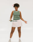 A woman smiling and wearing a sleeveless tank top with green and yellow stripes and a solid white neckline and armholes.