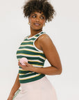A woman smiling and wearing a sleeveless tank top with green and yellow stripes and a solid white neckline and armholes.