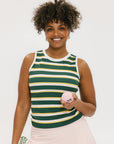 A woman smiling and wearing a sleeveless tank top with green and yellow stripes and a solid white neckline and armholes.