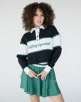 A person wearing a long sleeve polo shirt with horizontal green and white stripes and the text 'Golfing Optional' on the chest, paired with a green skirt.