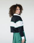 A person wearing a long sleeve polo shirt with horizontal green and white stripes and the text 'Golfing Optional' on the chest, paired with a green skirt.
