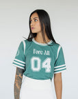 A woman wearing a green sporty top with text 'Fore All 04' and stripes, paired with a white skirt.
