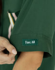A woman wearing a green button-up shirt with a collar and front pocket, paired with striped pants.