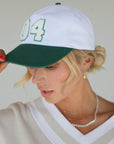 Close-up of the 'Weirsy Hat' from the Royal Collection, inspired by autumn hues. This hat retains the coveted fit of the best-selling Fore Hat but adds a vintage feel with an '04' patch. Combining classic style with an updated design, it's a must-have accessory for any golf enthusiast.