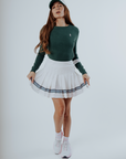 White pleated skirt with blue stripes worn by a person on a plain background