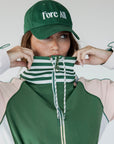 A person wearing a green Elle Rain Jacket with a matching green hat, standing against a white background.