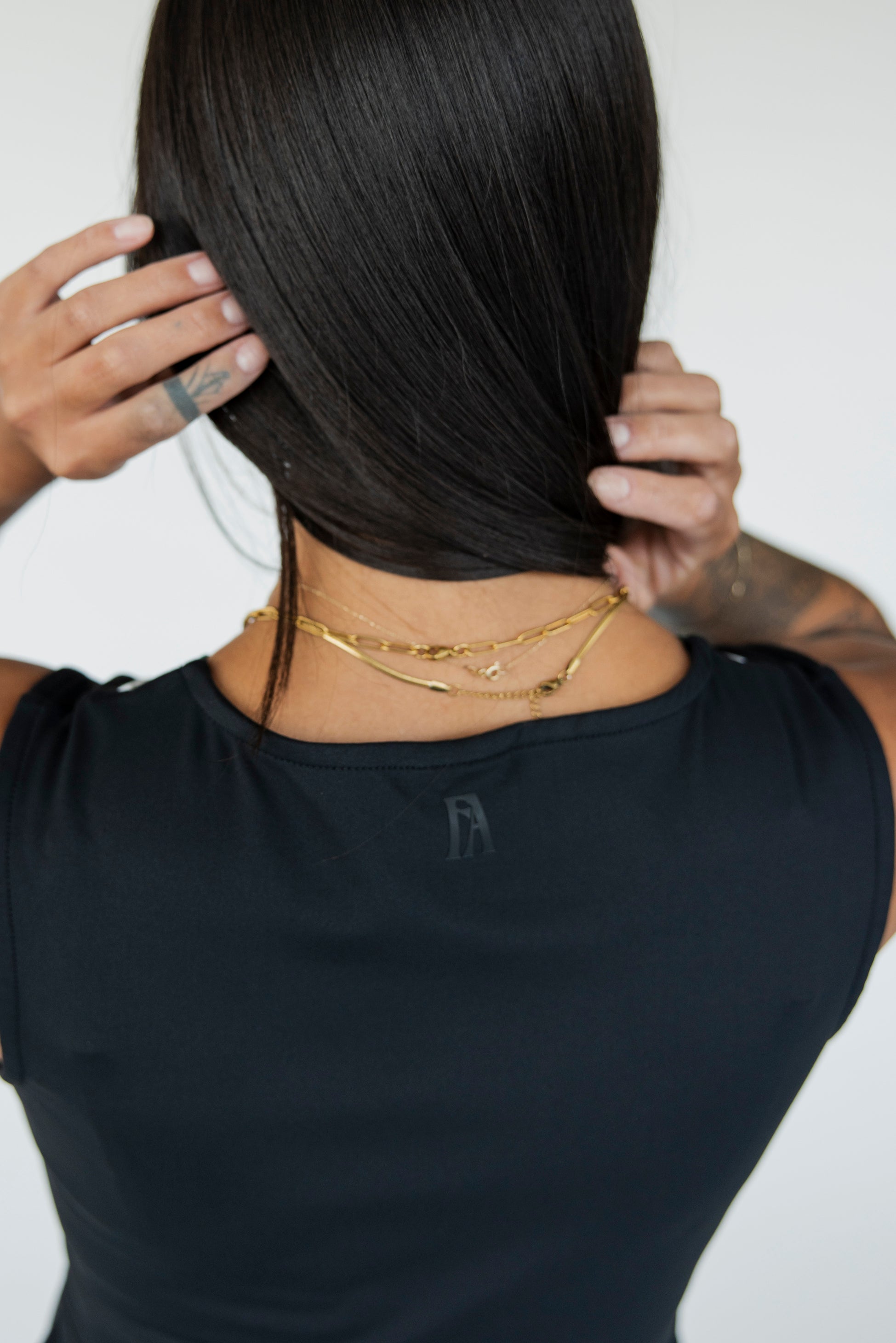 A model wearing a black sleeveless dress.