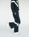 A model wearing a black sweatpant with green and white stripe details, paired with a matching sweatshirt.