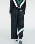 A model wearing a black sweatpant with green and white stripe details, paired with a matching sweatshirt.