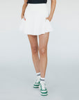 A woman wearing a white high-waisted skirt with built-in shorties and side seam pockets, paired with a black top.