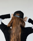 Black and green cap with 'GET OFF MY BACK' text worn by a model.