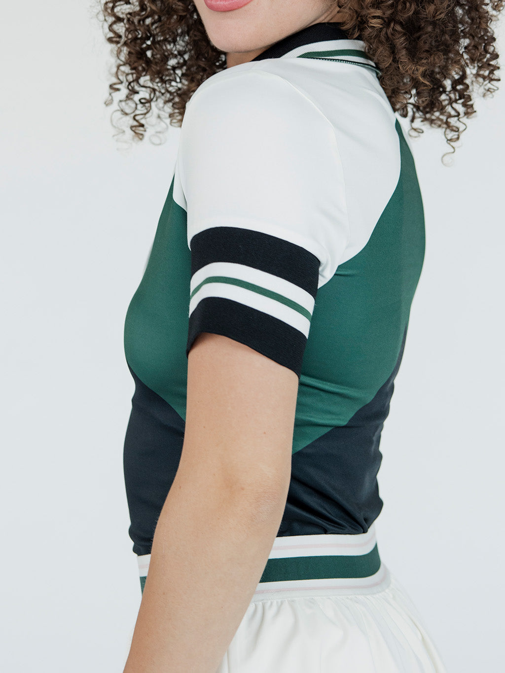 A woman wearing a green, black, and white striped Betty Polo shirt with a preppy collar.