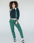A female model wearing a black and green color-blocked crew neck golf shirt with long sleeves.