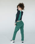 A female model wearing a black and green color-blocked crew neck golf shirt with long sleeves.