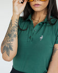 A woman wearing a green polo shirt with a collar, featuring a four-button placket and puff sleeves, paired with a black skirt.