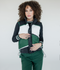 A female model wearing a color-blocked puffer vest in green, black, and white, paired with green pants.