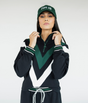 A person wearing a black sweatshirt with green and white details, including a quarter-zip design and chevron patterns, paired with a matching hat.