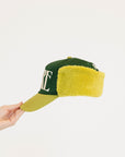 Green and avocado cap with 'FORE' text held by a hand on a white background
