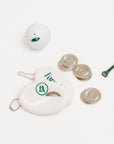 White coin purse with gold rings and a white ball on a light gray background