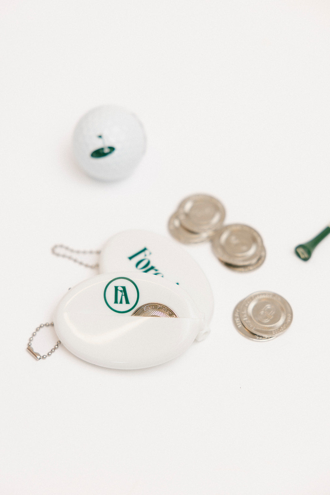 White coin purse with gold rings and a white ball on a light gray background