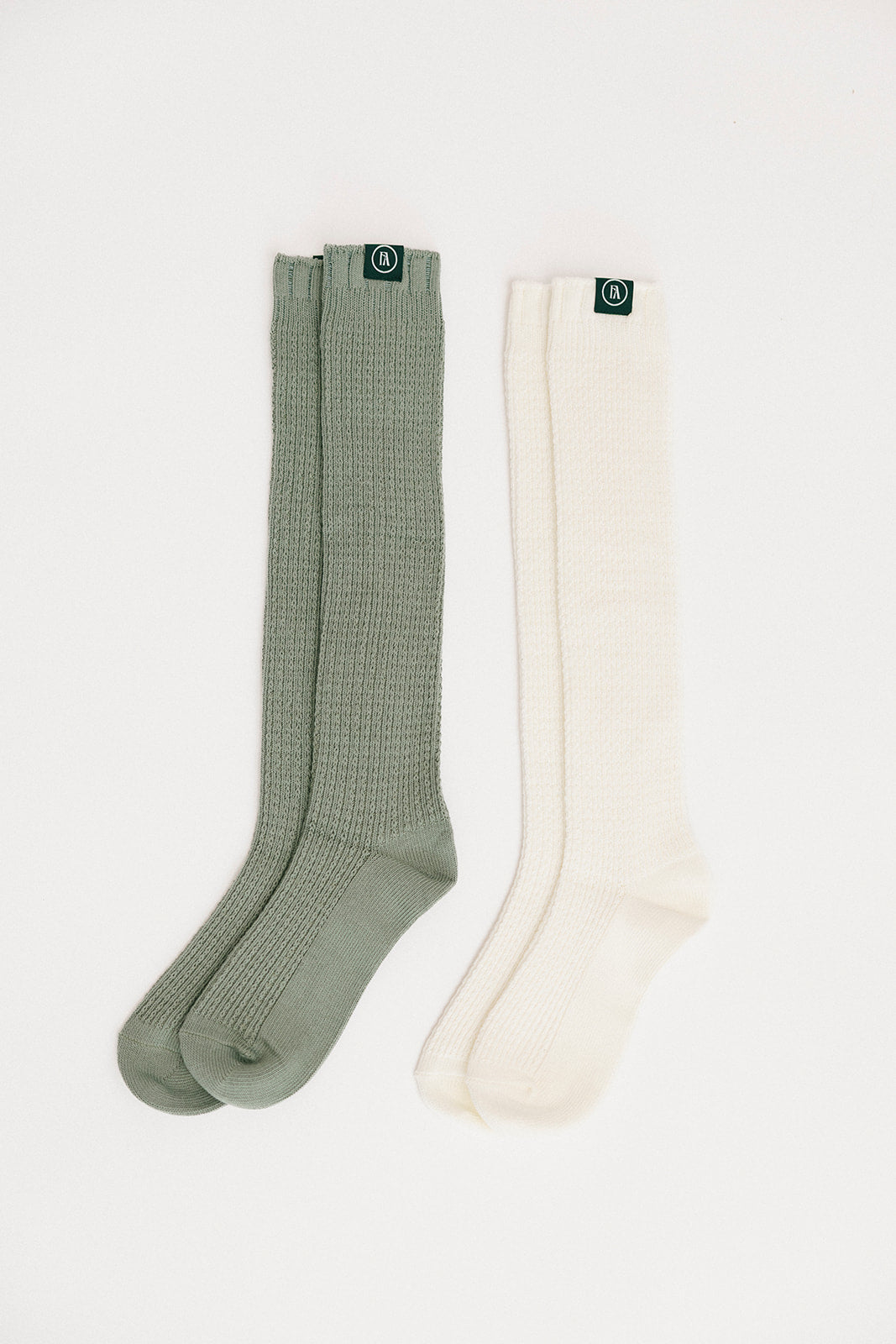 Two pairs of knee-high socks, one green and one white, on a light gray background.