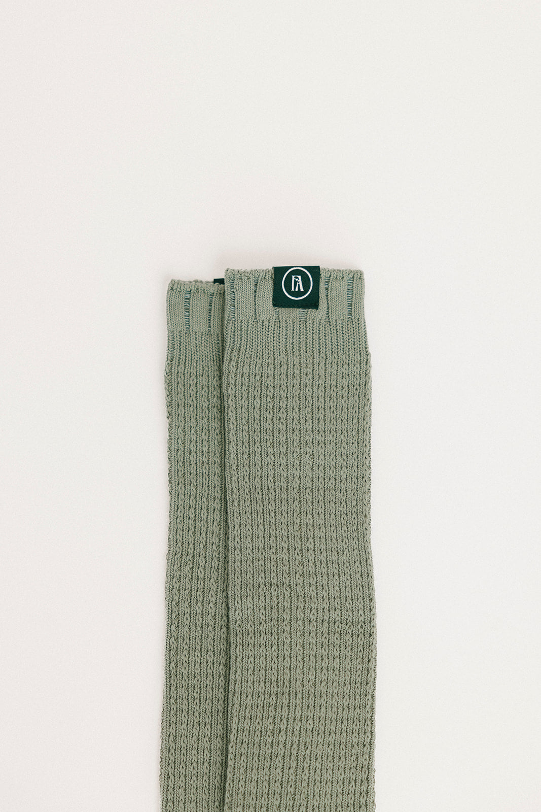 Green textured sock with a brand logo on a light beige background