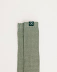 Green textured sock with a brand logo on a light beige background
