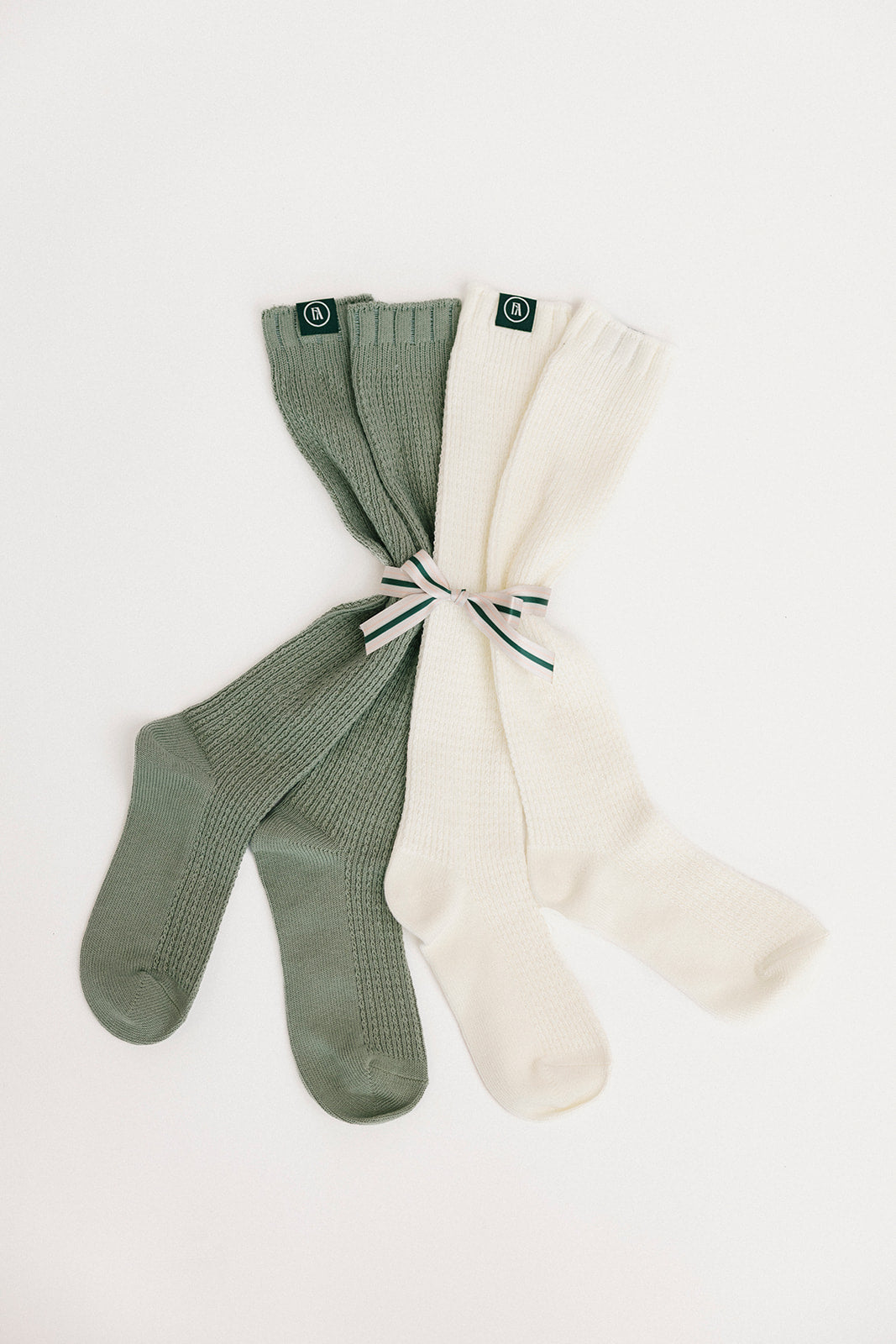 Two pairs of socks, one green and one white, on a light gray background.