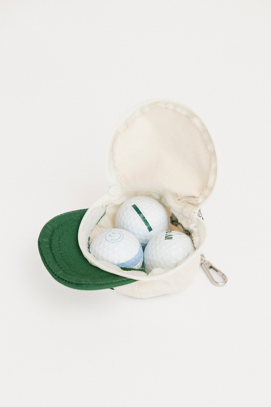 Canvas bag with golf balls and a green cap on a white background