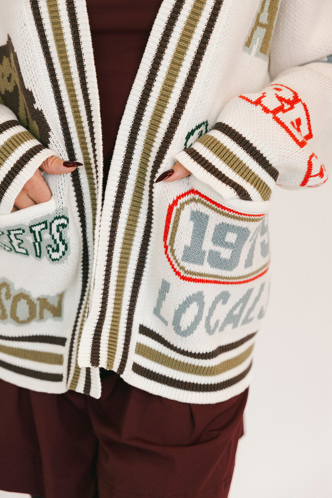 Person wearing a patterned cardigan with text and numbers on a white background