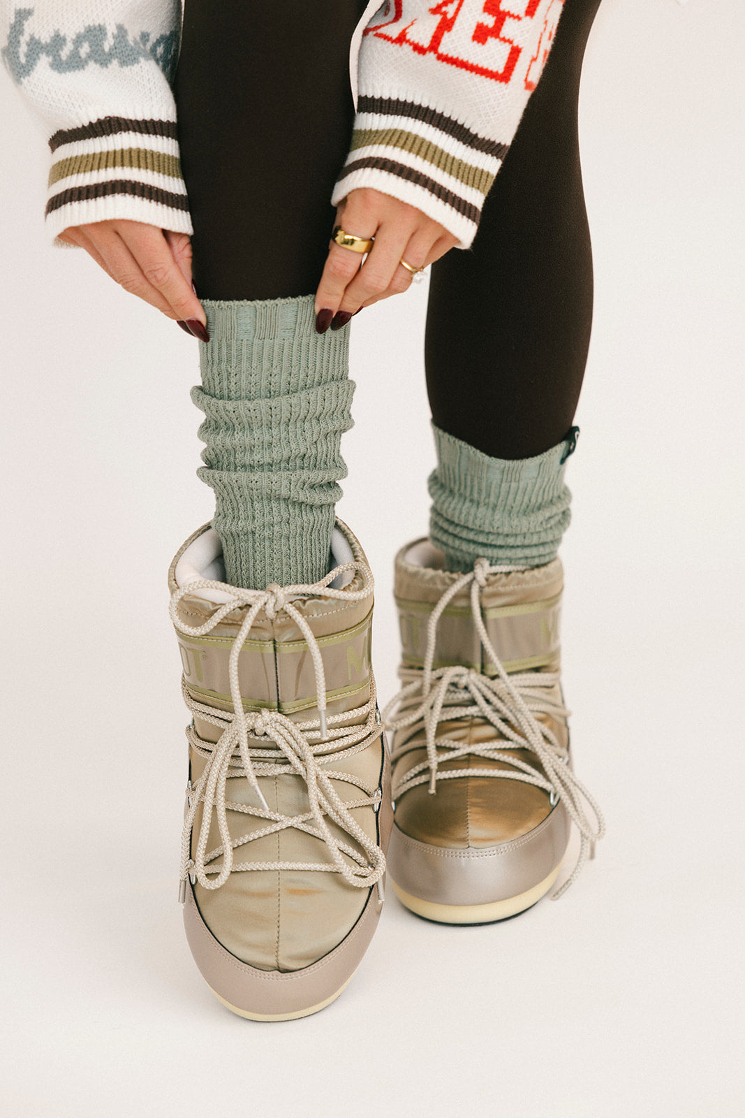 Person wearing high socks, boots, and a patterned sweater on a white background