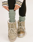 Person wearing high socks, boots, and a patterned sweater on a white background